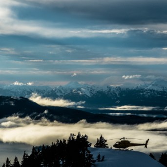 a group of clouds in the sky over a snow covered mountain
